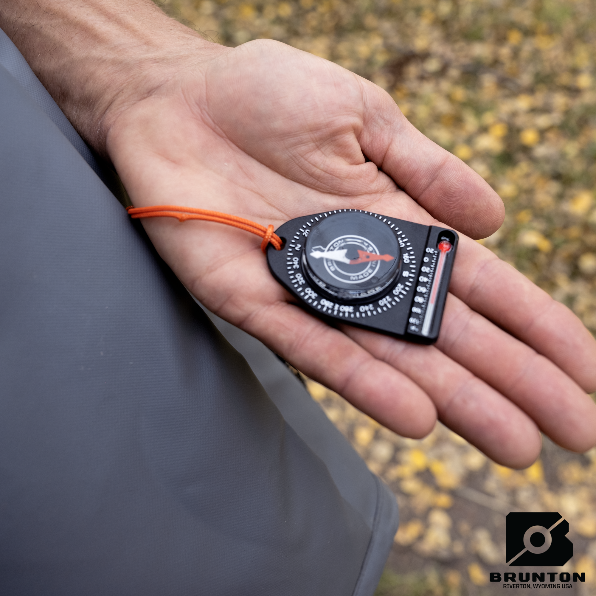 Person holding a Brunton compass in their hand