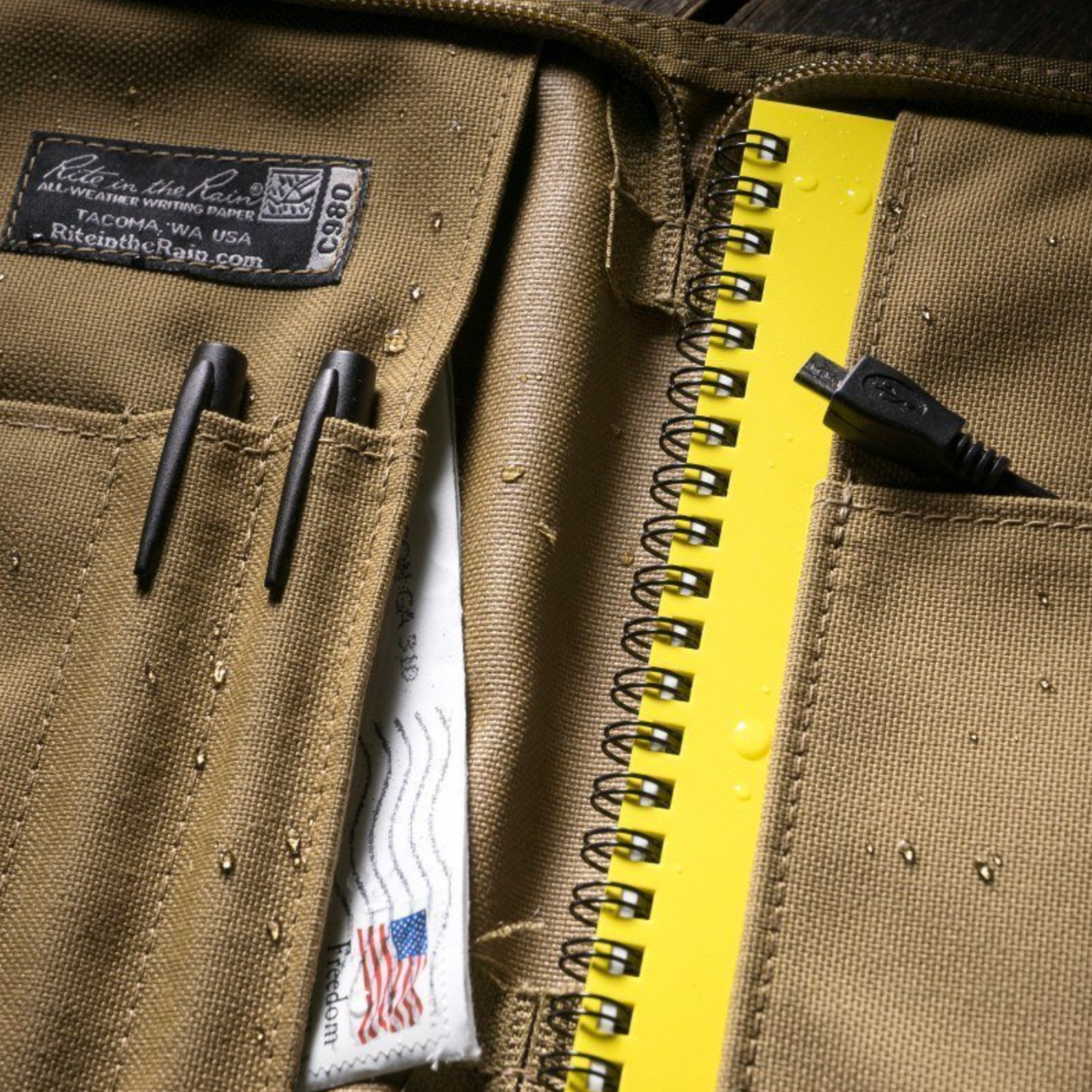Close-up of a tan cover with pens and notebook in pockets