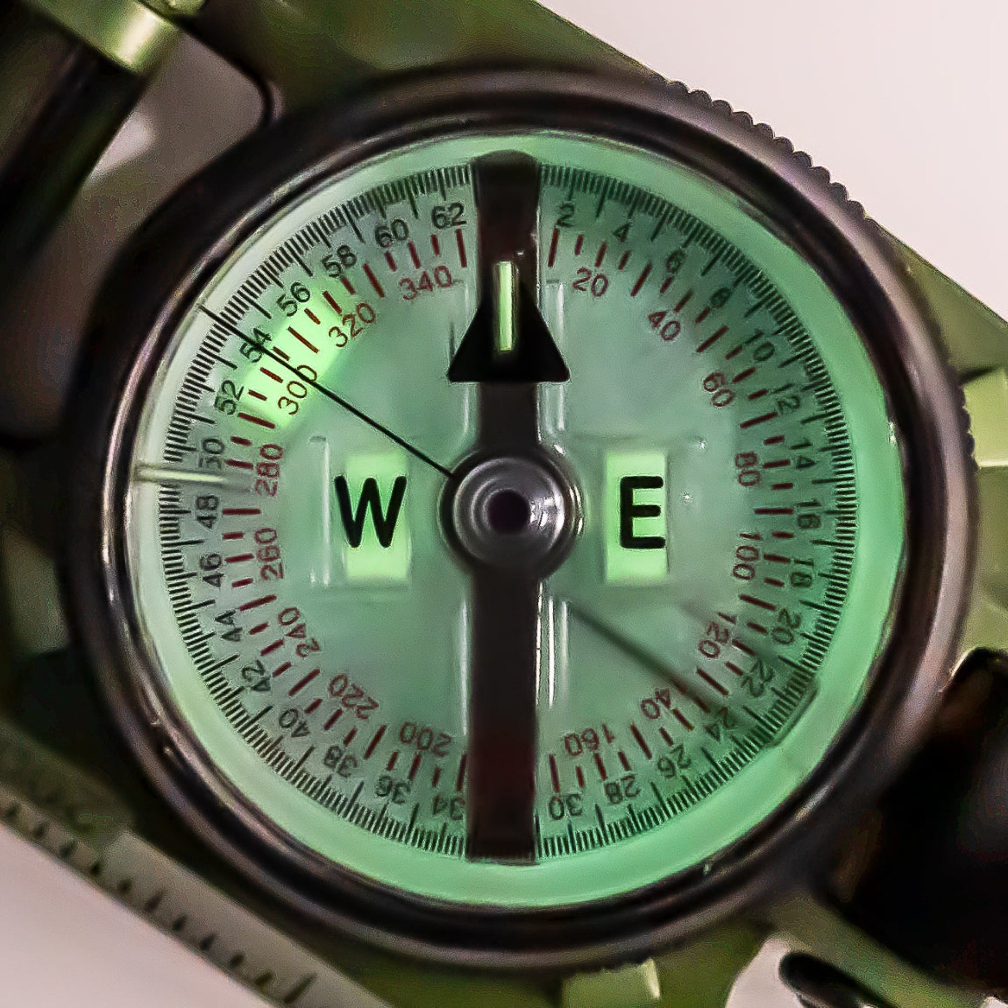Close-up of a compass with a green dial and black bezel.