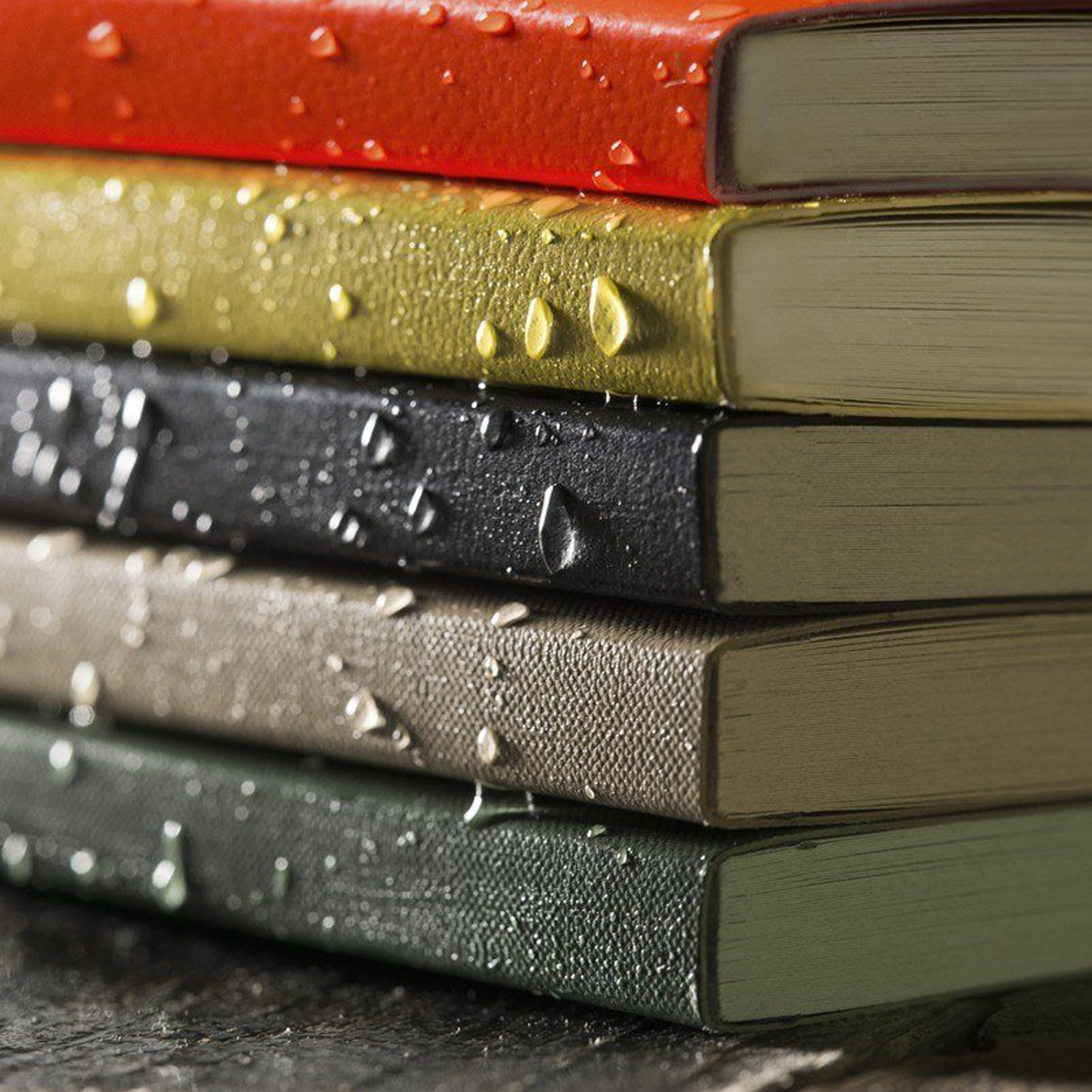 Stack of memo books with water droplets on a dark surface